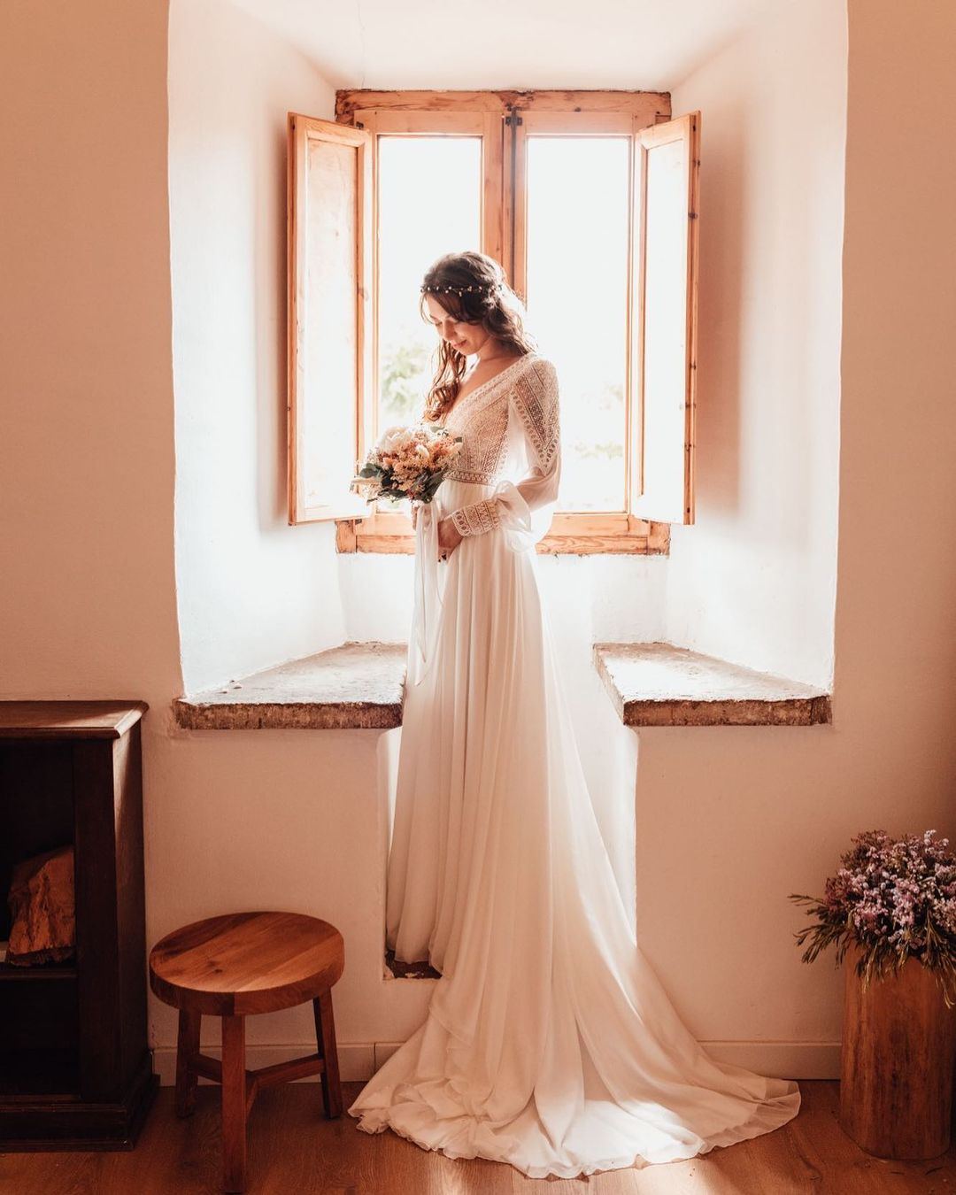 Novia junto a la ventana con ramo de flores