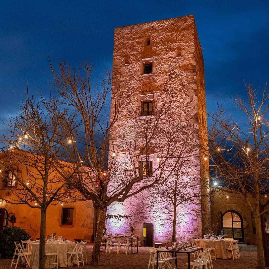 Torre iluminada al anochecer con mesas montadas